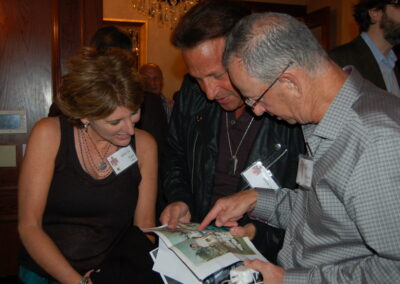 40th reunion at Maggiano's, three people examining an old team photo.